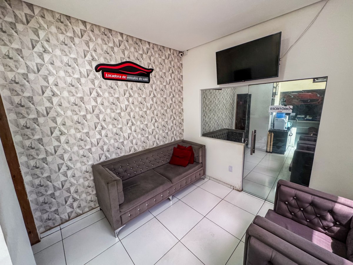 Sala de espera com sofá e a logo da locadora na parede